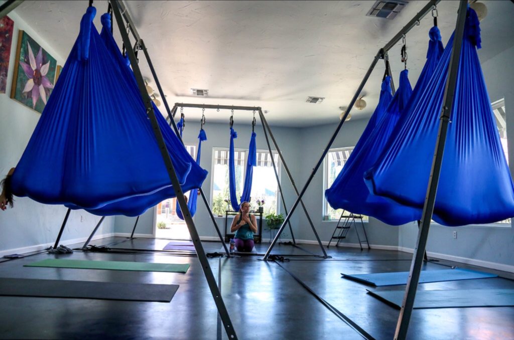 Anne teaching an aerial yoga class in a yoga studio. All of the students are in savasana. 